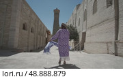 A young woman with long hair in an oriental robe and a skullcap walks through an ancient oriental city. Стоковое видео, видеограф Aleksey Kidisyuk / Фотобанк Лори