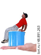 Worker with cap sat on paint can. Стоковое фото, агентство Ingram Publishing / Фотобанк Лори