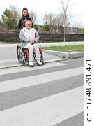 Woman waiting at a zebra crossing with an elderly lady in a wheelchair. Стоковое фото, агентство Ingram Publishing / Фотобанк Лори