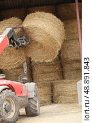 Tractor lifting bail of hay. Стоковое фото, агентство Ingram Publishing / Фотобанк Лори