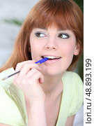 Young woman chewing on a pen. Стоковое фото, агентство Ingram Publishing / Фотобанк Лори