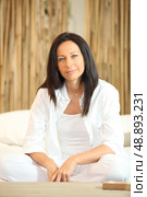 Woman in white clothing sat on white sofa. Стоковое фото, агентство Ingram Publishing / Фотобанк Лори