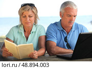 Young couple with book and computer. Стоковое фото, агентство Ingram Publishing / Фотобанк Лори