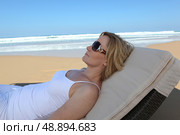 Woman relaxing on a sun lounger on the beach. Стоковое фото, агентство Ingram Publishing / Фотобанк Лори