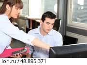 Woman explaining something on a computer to her colleague. Стоковое фото, агентство Ingram Publishing / Фотобанк Лори