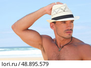 Muscular man posing on the beach in a panama hat. Стоковое фото, агентство Ingram Publishing / Фотобанк Лори