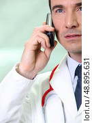 Serious doctor using a cellphone. Стоковое фото, агентство Ingram Publishing / Фотобанк Лори
