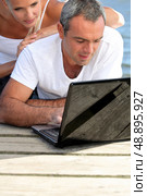 Man lying with a woman behind computer. Стоковое фото, агентство Ingram Publishing / Фотобанк Лори