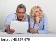 Middle aged couple with a laptop on their bed. Стоковое фото, агентство Ingram Publishing / Фотобанк Лори