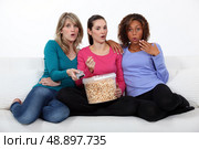 Three woman eating popcorn whilst watching film. Стоковое фото, агентство Ingram Publishing / Фотобанк Лори