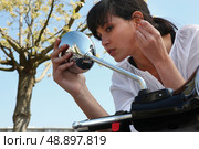 Woman looking in rearview mirror of a scooter. Стоковое фото, агентство Ingram Publishing / Фотобанк Лори