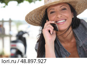 Woman wearing a straw hat talking on her mobile phone. Стоковое фото, агентство Ingram Publishing / Фотобанк Лори