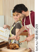 Couple cooking roast chicken. Стоковое фото, агентство Ingram Publishing / Фотобанк Лори