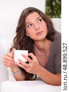 Woman drinking a coffee on a sofa. Стоковое фото, агентство Ingram Publishing / Фотобанк Лори
