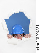Tradesman peeking out through an opening in a wall. Стоковое фото, агентство Ingram Publishing / Фотобанк Лори
