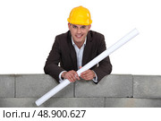 Proud architect stood by wall with rolled-up blueprints. Стоковое фото, агентство Ingram Publishing / Фотобанк Лори
