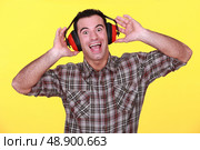 happy man wearing earmuffs cancelling noise. Стоковое фото, агентство Ingram Publishing / Фотобанк Лори