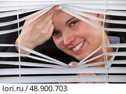 Happy woman peering through blinds. Стоковое фото, агентство Ingram Publishing / Фотобанк Лори