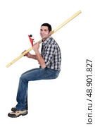 Man holding a wooden plank and a plane while sitting on a block. Стоковое фото, агентство Ingram Publishing / Фотобанк Лори