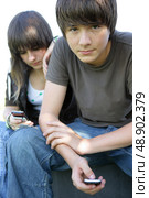Teenage couple texting on their cellphones. Стоковое фото, агентство Ingram Publishing / Фотобанк Лори