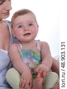 Mother resting baby daughter on knee. Стоковое фото, агентство Ingram Publishing / Фотобанк Лори