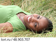 Beautiful smiling woman laying in the long grass. Стоковое фото, агентство Ingram Publishing / Фотобанк Лори