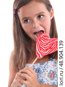 Girl about to lick a heart lollipop. Стоковое фото, агентство Ingram Publishing / Фотобанк Лори