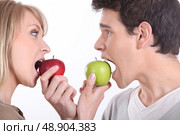 Man and woman about to bite into apples. Стоковое фото, агентство Ingram Publishing / Фотобанк Лори