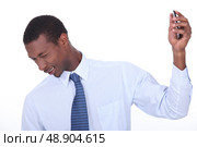 excited black man wincing and holding a cell phone in his hand. Стоковое фото, агентство Ingram Publishing / Фотобанк Лори