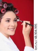 Woman in curlers applying eyeshadow. Стоковое фото, агентство Ingram Publishing / Фотобанк Лори