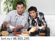 Father and son playing video games. Стоковое фото, агентство Ingram Publishing / Фотобанк Лори