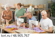 Elderly participants in sewing coterie learn sewing, communicate and talking, sewing, cut fabric by scissors. Стоковое фото, фотограф Яков Филимонов / Фотобанк Лори