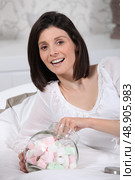 Woman eating marshmallows in bed. Стоковое фото, агентство Ingram Publishing / Фотобанк Лори