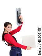 Tradeswoman holding up a tile cutting machine and a tile. Стоковое фото, агентство Ingram Publishing / Фотобанк Лори