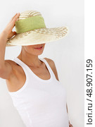 Shy woman pushing hat over face. Стоковое фото, агентство Ingram Publishing / Фотобанк Лори
