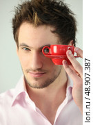 Man looking through the handle of a coffee cup. Стоковое фото, агентство Ingram Publishing / Фотобанк Лори