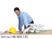 Annoyed architect piling rolled-up drawings on a model. Стоковое фото, агентство Ingram Publishing / Фотобанк Лори