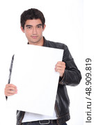 Young man in a leather jacket holding a board left blank for your message. Стоковое фото, агентство Ingram Publishing / Фотобанк Лори