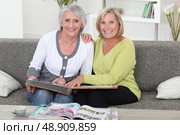 Mother and daughter looking at a picture album together. Стоковое фото, агентство Ingram Publishing / Фотобанк Лори
