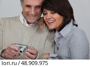 Married couple looking at photographs taken on digital camera. Стоковое фото, агентство Ingram Publishing / Фотобанк Лори