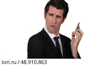 Businessman grimacing at his phone. Стоковое фото, агентство Ingram Publishing / Фотобанк Лори