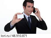 Businessman on the phone whilst showing a blank card. Стоковое фото, агентство Ingram Publishing / Фотобанк Лори