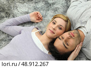 Young couple lying on grey carpet. Стоковое фото, агентство Ingram Publishing / Фотобанк Лори
