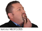 Businessman stroking his beard whilst thinking. Стоковое фото, агентство Ingram Publishing / Фотобанк Лори