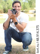 Photographer crouching in the countryside. Стоковое фото, агентство Ingram Publishing / Фотобанк Лори