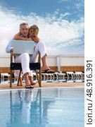 Couple looking at a laptop by a pool. Стоковое фото, агентство Ingram Publishing / Фотобанк Лори