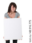 Brunette winking whilst holding advertising panel. Стоковое фото, агентство Ingram Publishing / Фотобанк Лори