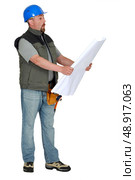 Tradesman examining a blueprint. Стоковое фото, агентство Ingram Publishing / Фотобанк Лори