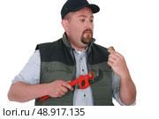 Apprehensive handyman staring at an object. Стоковое фото, агентство Ingram Publishing / Фотобанк Лори