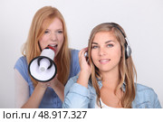 Young girl oblivious to her friend yelling into a megaphone. Стоковое фото, агентство Ingram Publishing / Фотобанк Лори